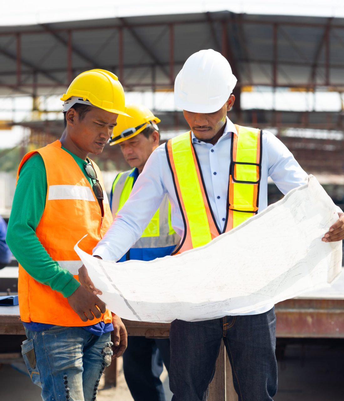 Professional Engineer Team working. Young architect Engineering and asian worker in safety hardhat and  looking at blueprint at industrial Heavy Manufacturing Factory. Prefabricated concrete walls